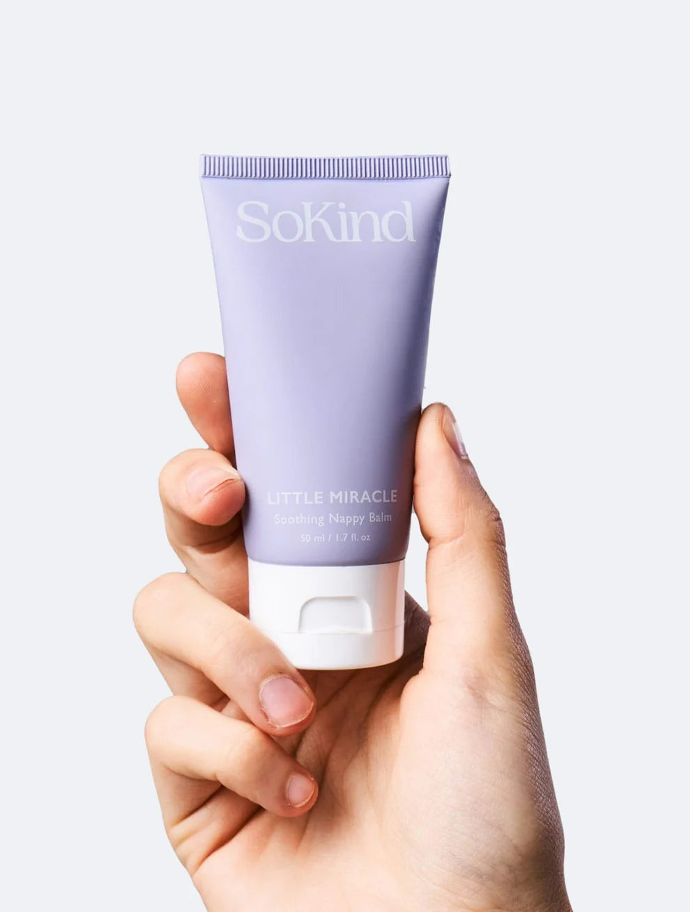 De Little Miracle luierbalsem tube van SoKind wordt vastgehouden door een hand.