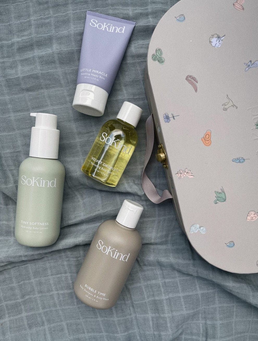 De vier SoKind producten van de Dear Baby Skin Care Kit naast een koffertje.