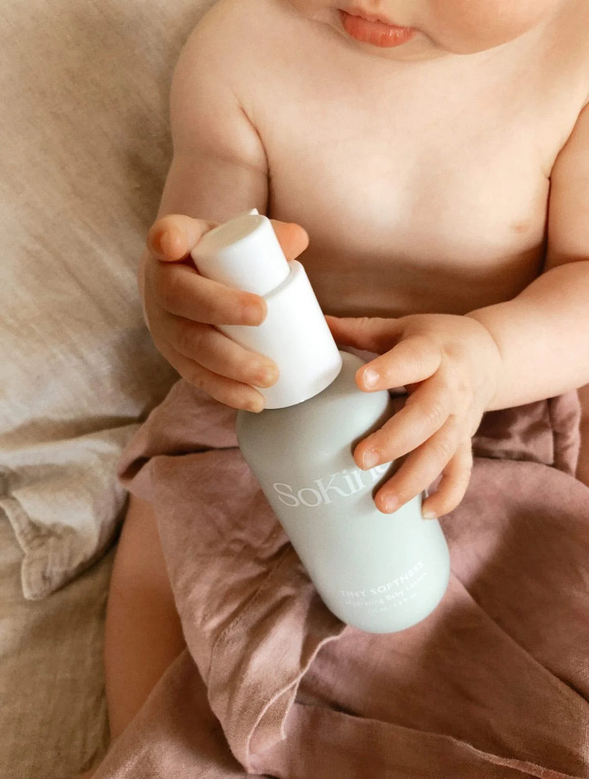 Baby die de Tiny Softness Babylotion van SoKind vasthoudt.