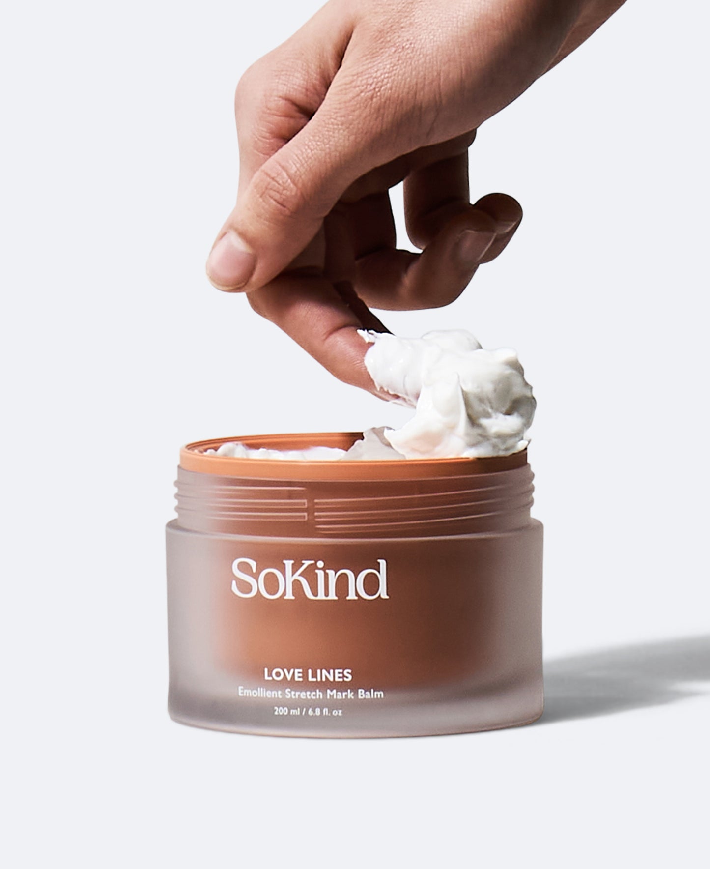 De Love Lines striemenzalf van SoKind met een hand die er wat crème uit haalt.
