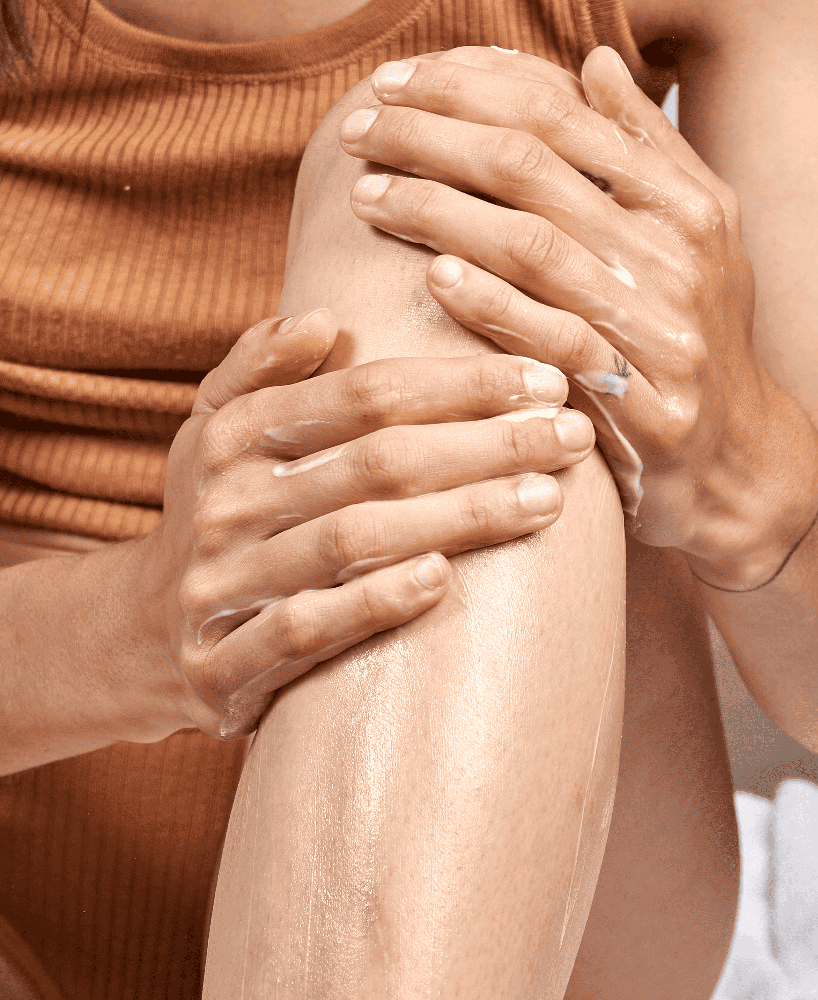 Vrouw die de Silky Essential Body Lotion van SoKind op haar onderbenen smeert.
